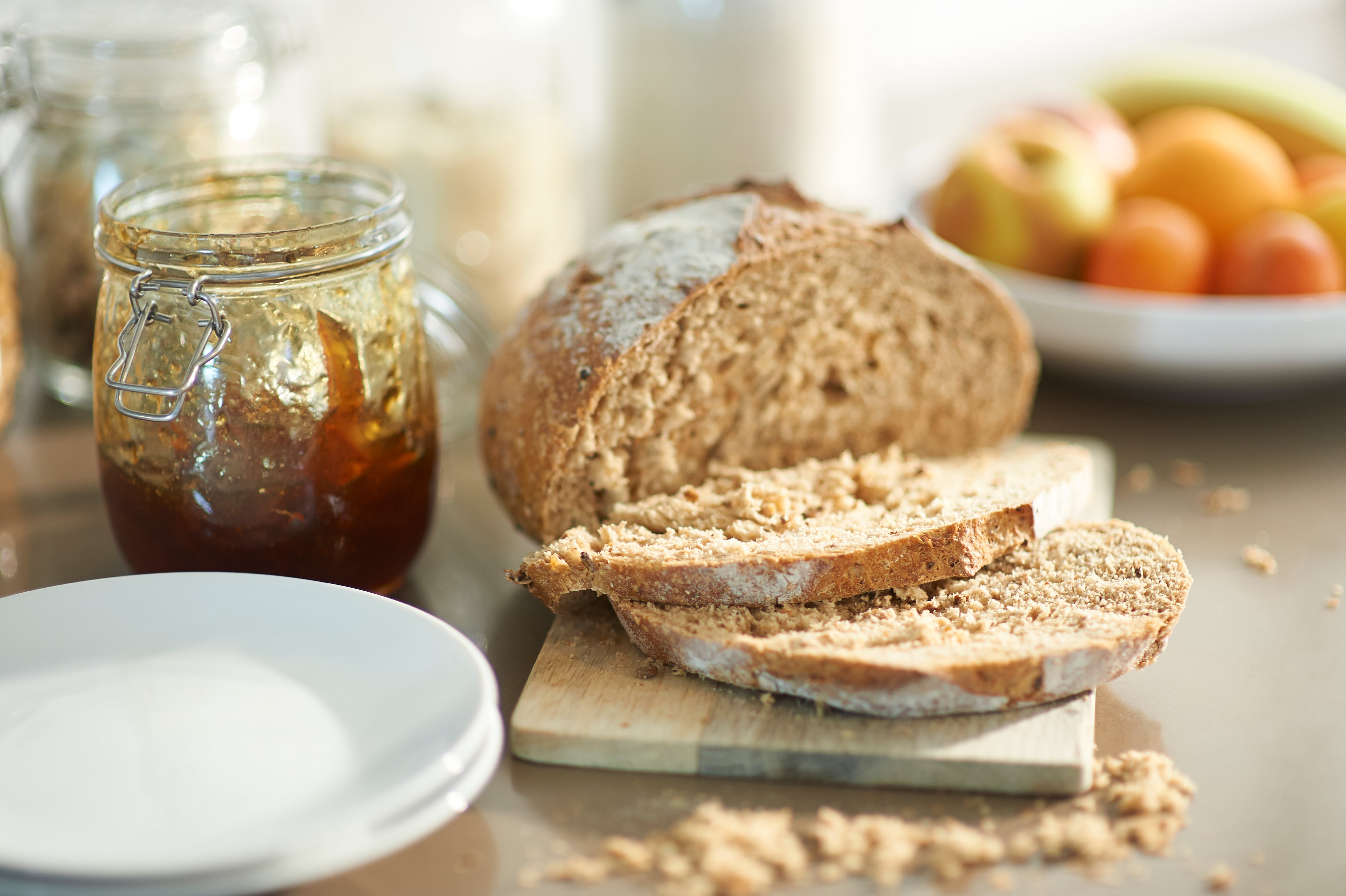 Sliced wholewheat loaf of bread with jam and fresh fruit in a zero waste kitchen.