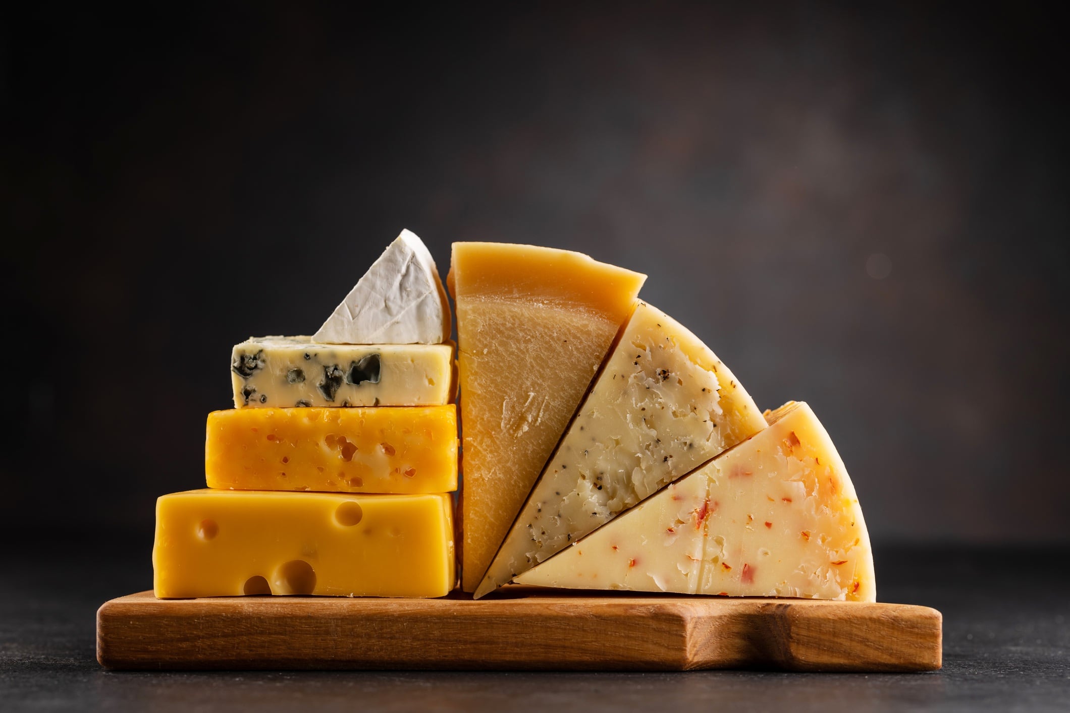 Various cheese on board on stone table.
