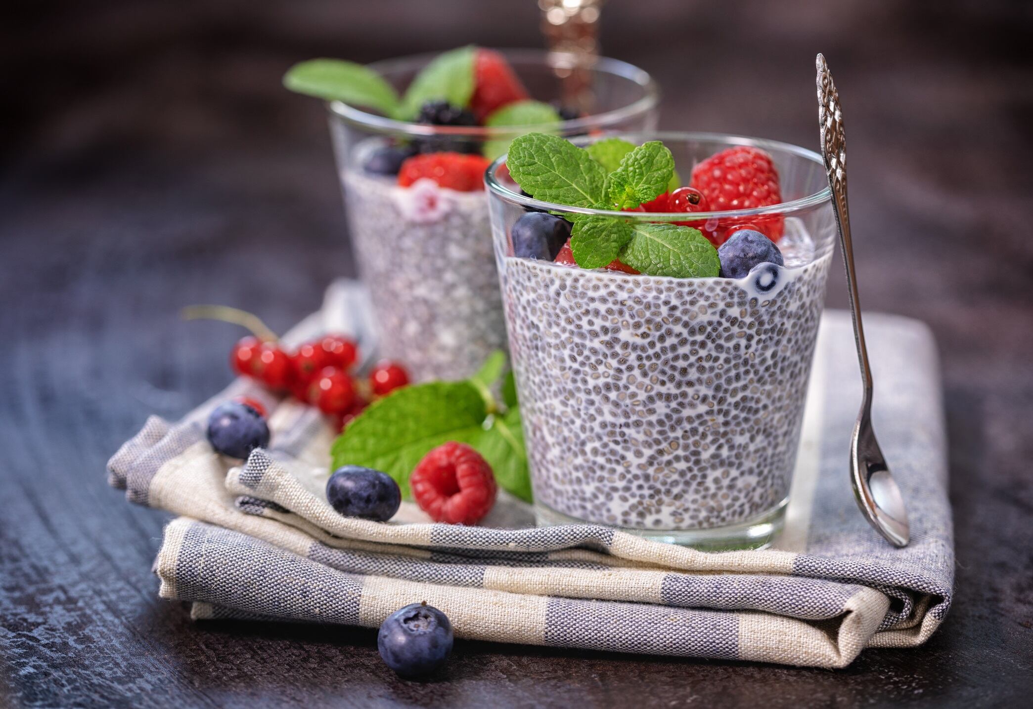 Two glasses of chia seed pudding with fresh berry fruits and mint topping for the breakfast.