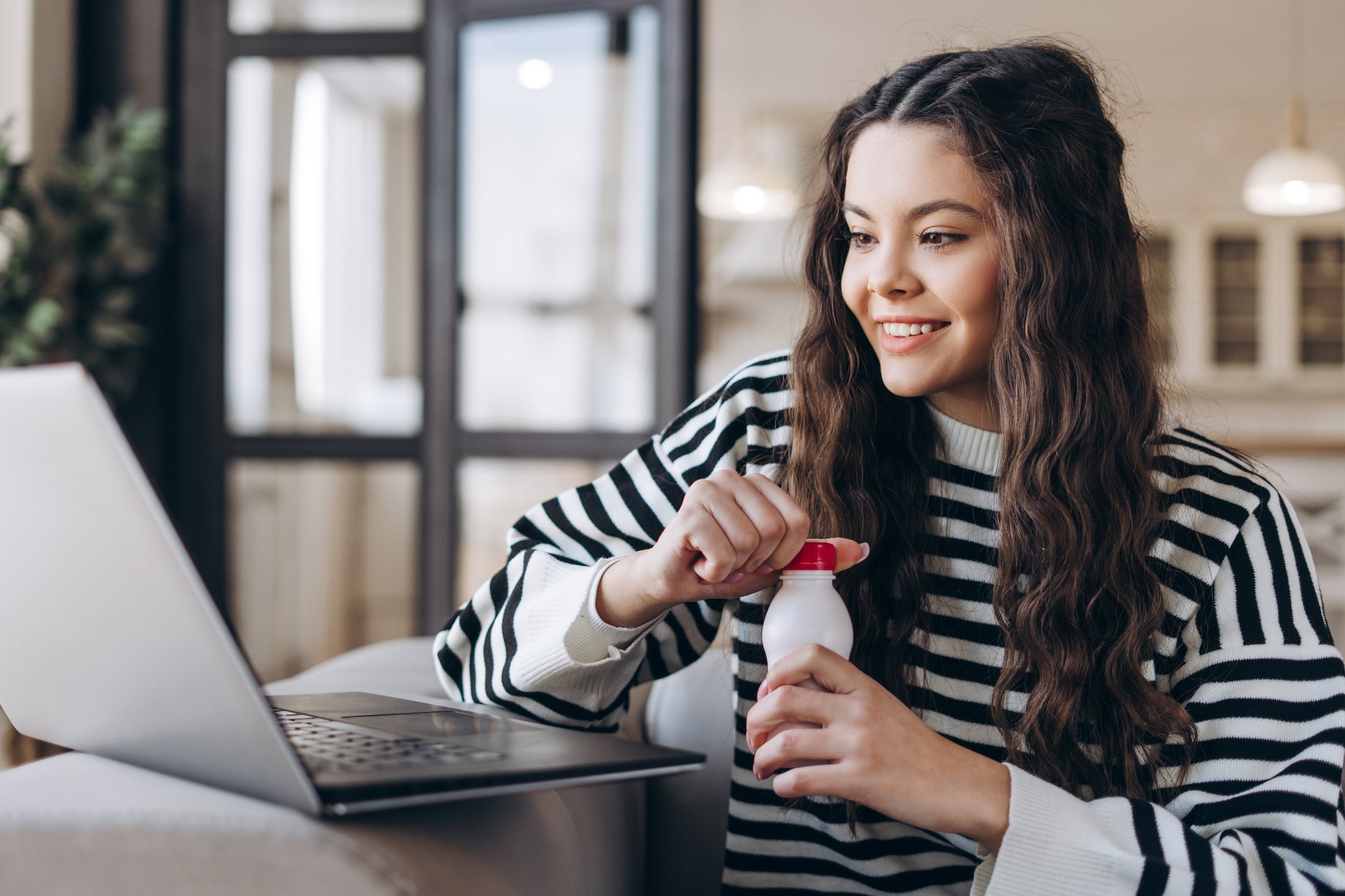 Smiling teenager sitting on sofa holding bottle