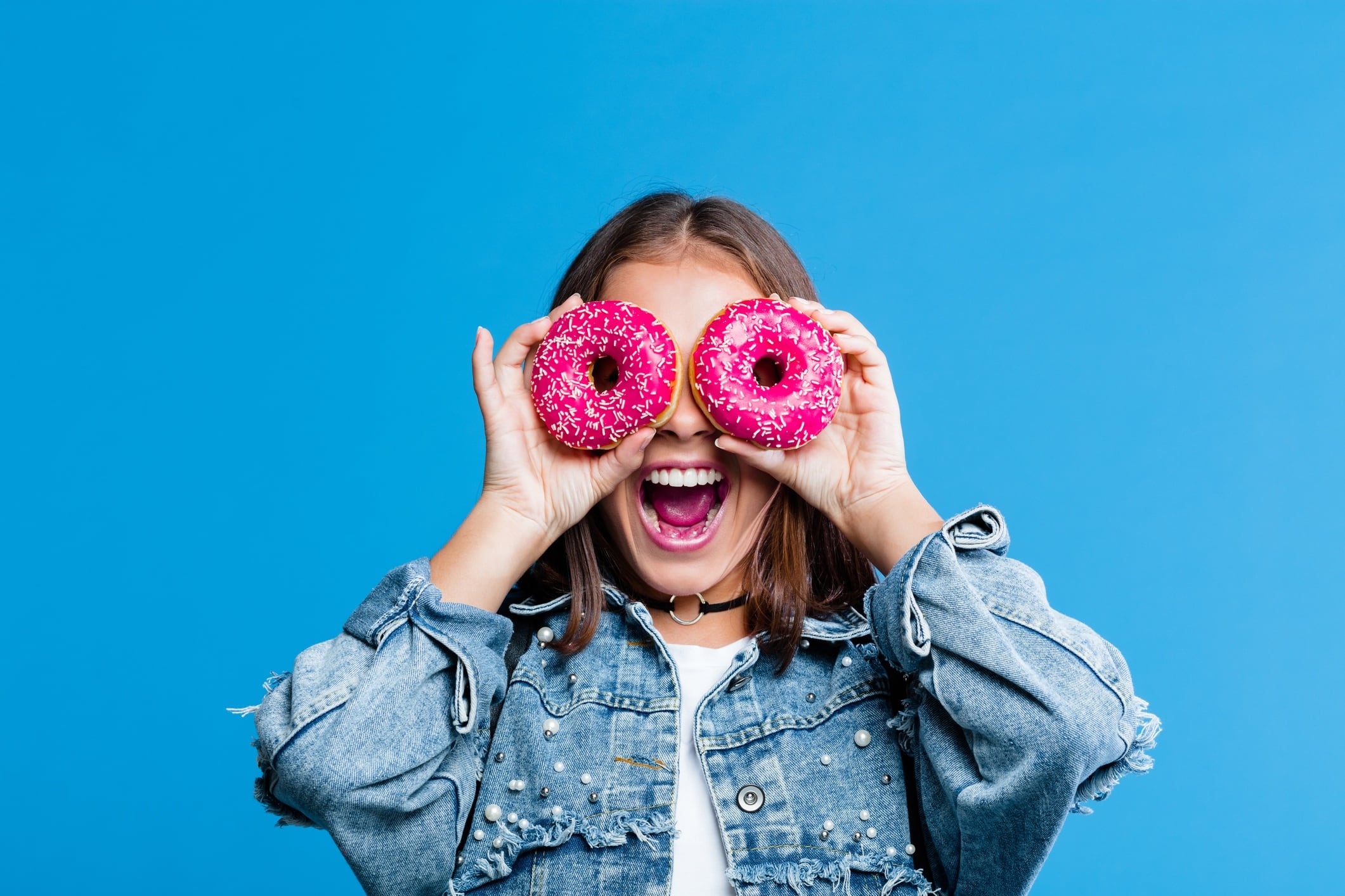 Woman covering her eyes with pink doughnuts