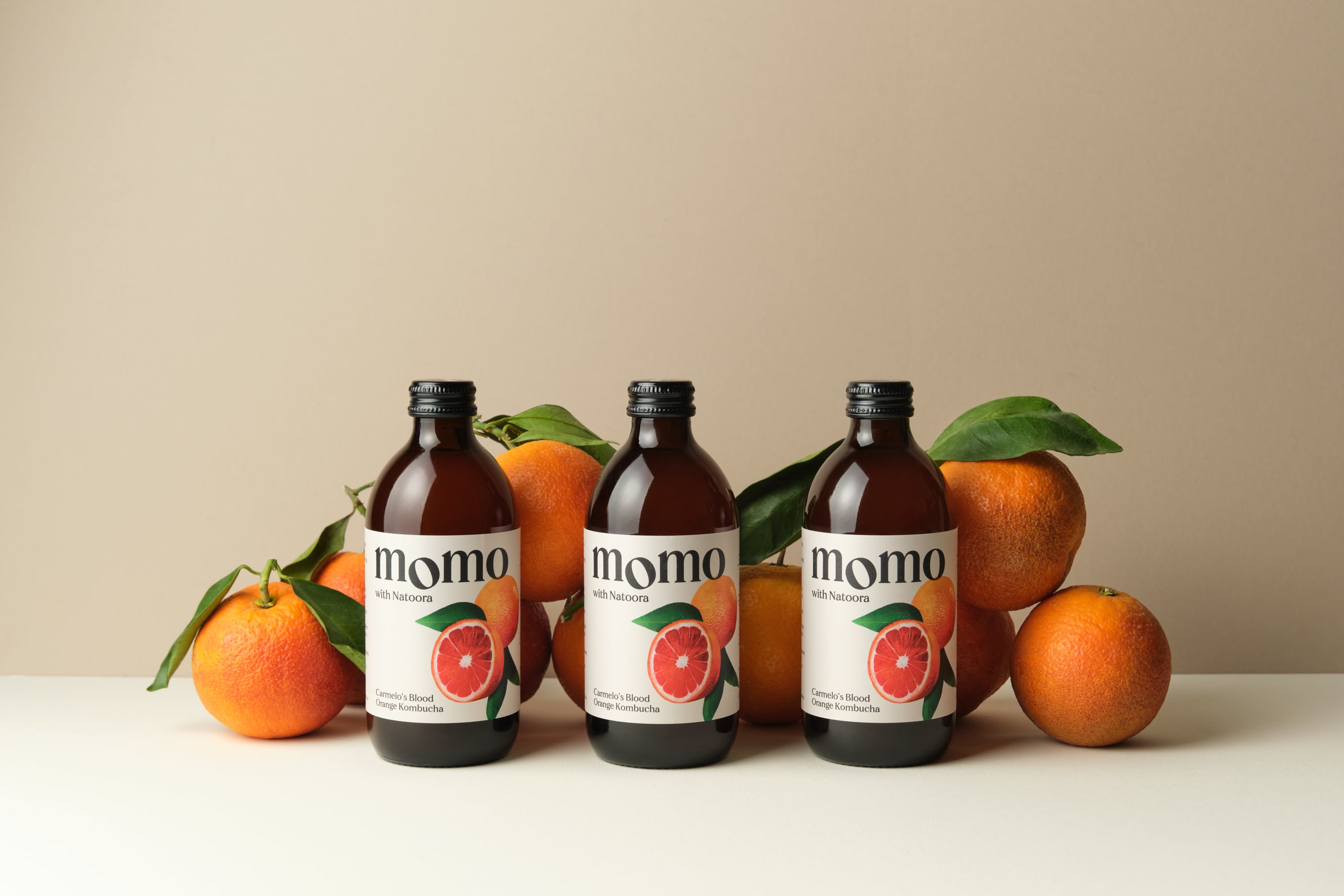MOMO x Natoora Blood Orange Kombucha in a glass bottle.