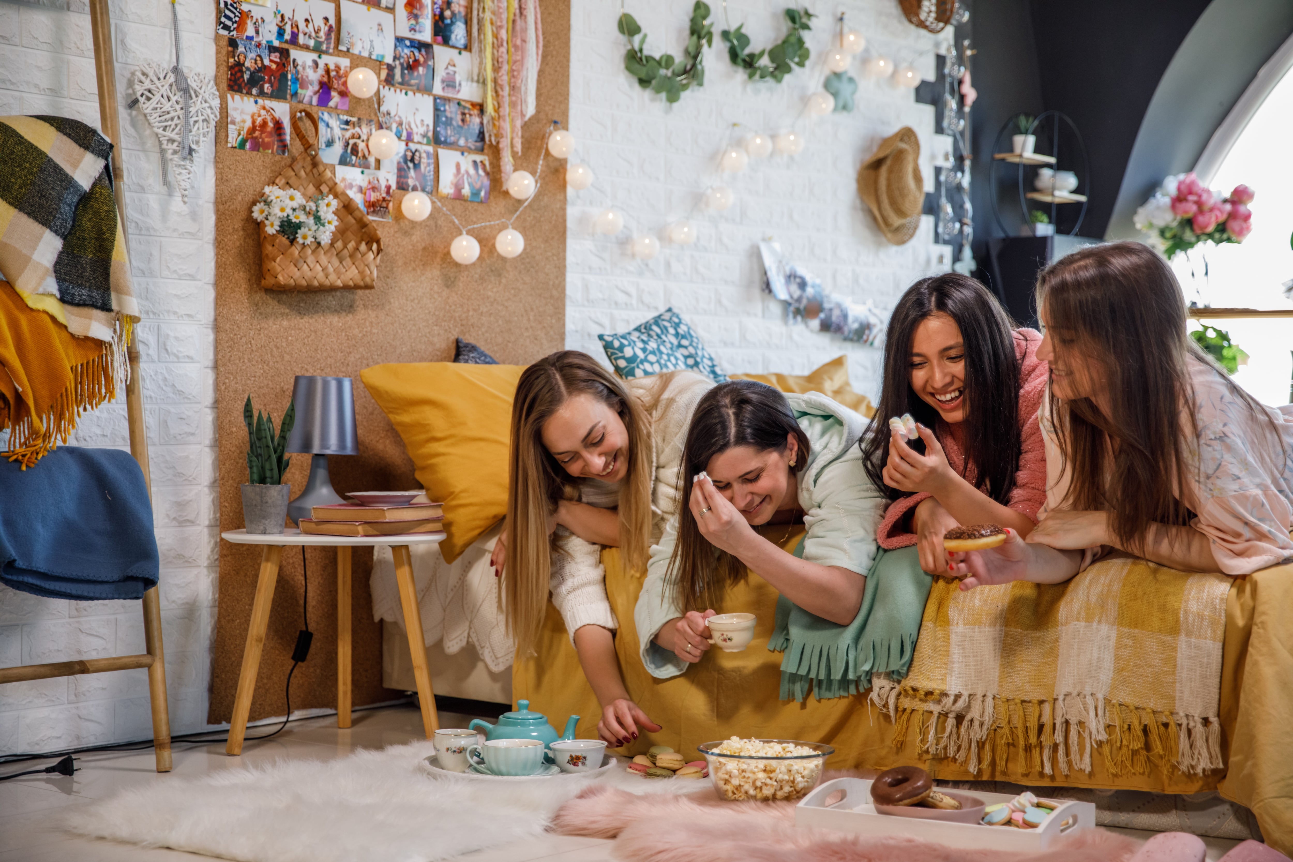 Four young women on a bed eating snacks