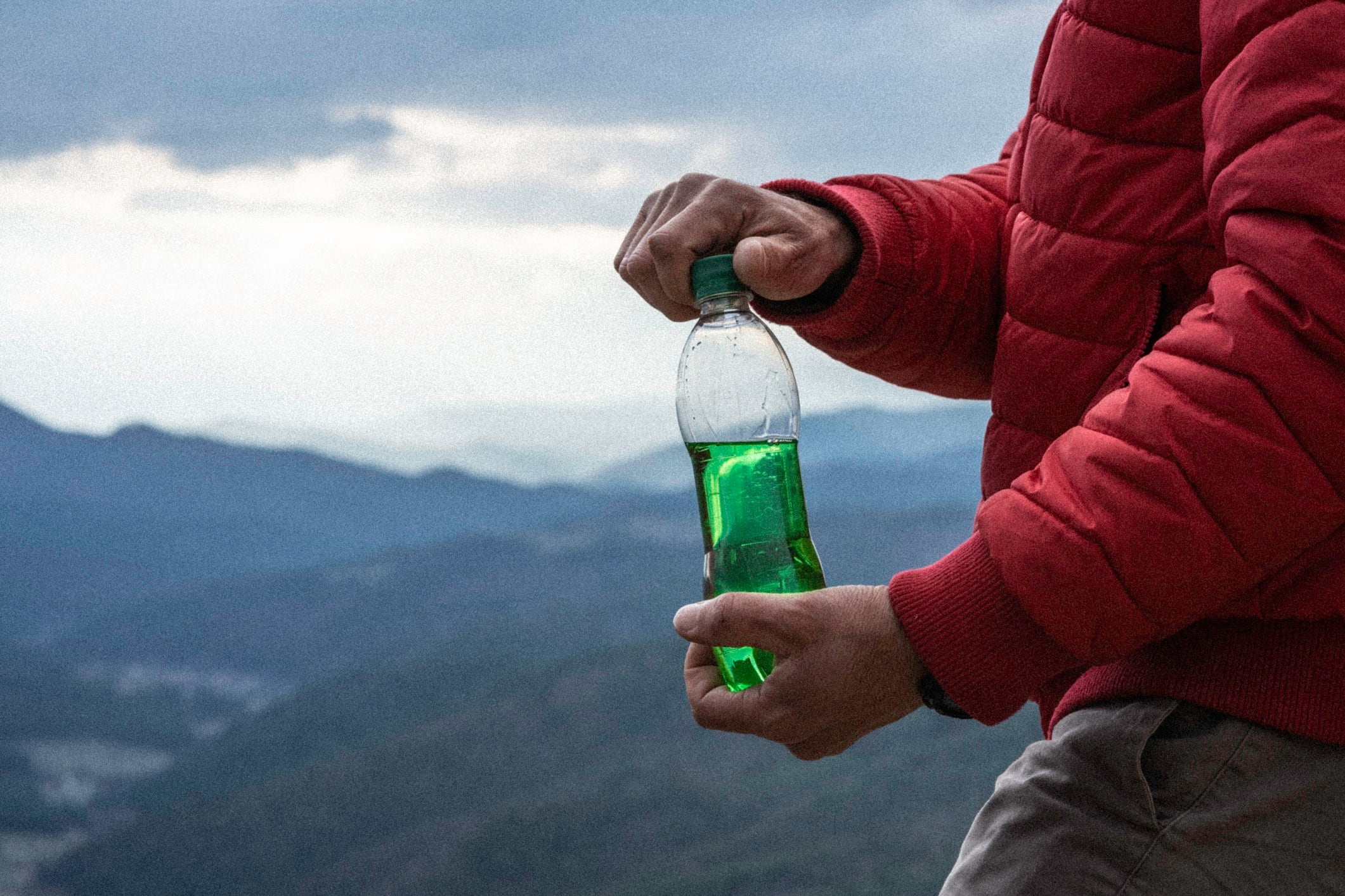 Beverage in bottle in front of mountains background.