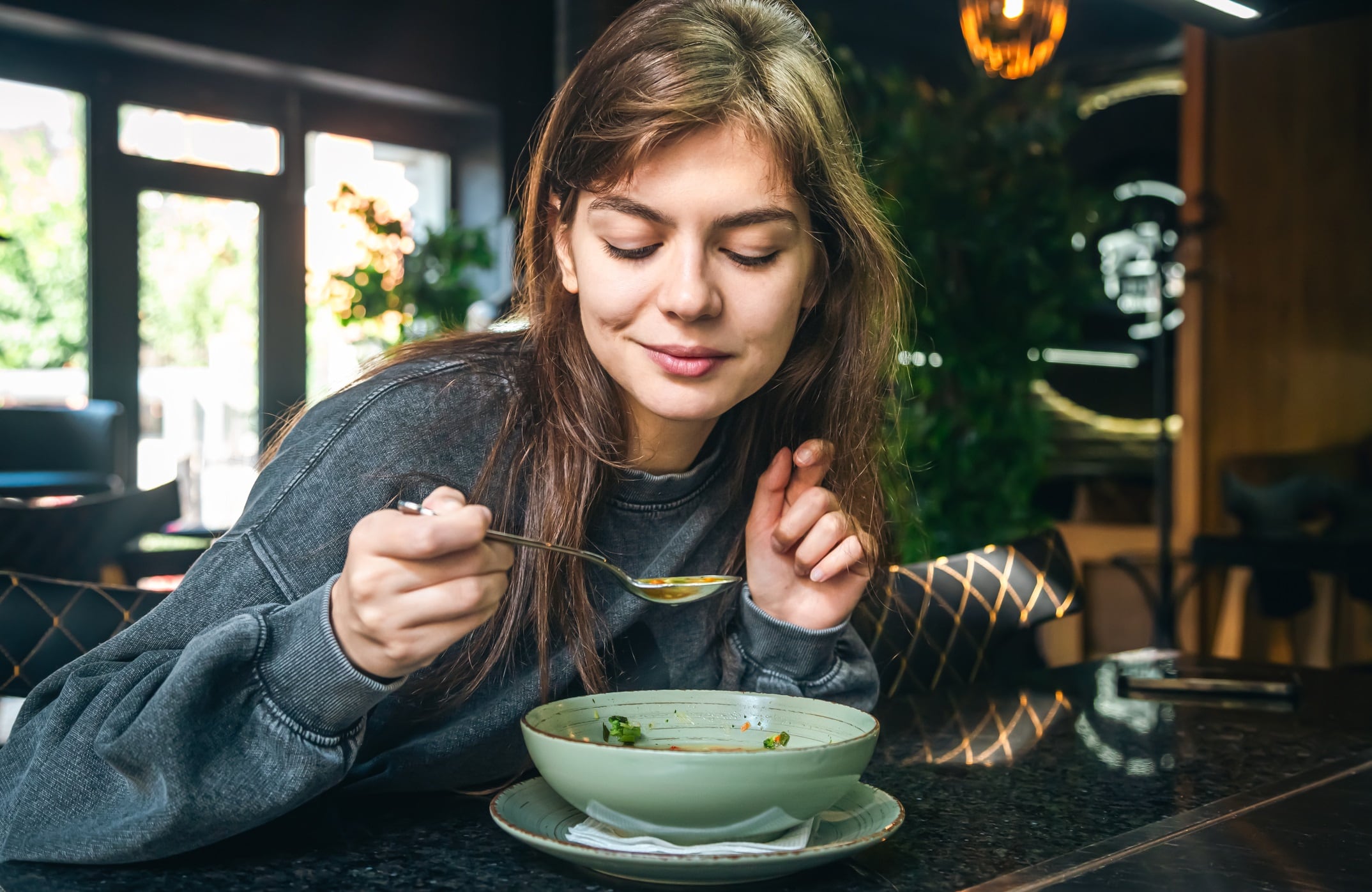 Woman eating vegetable soup in a cafe, healthy eating, veganism and vegetarianism, copy space.