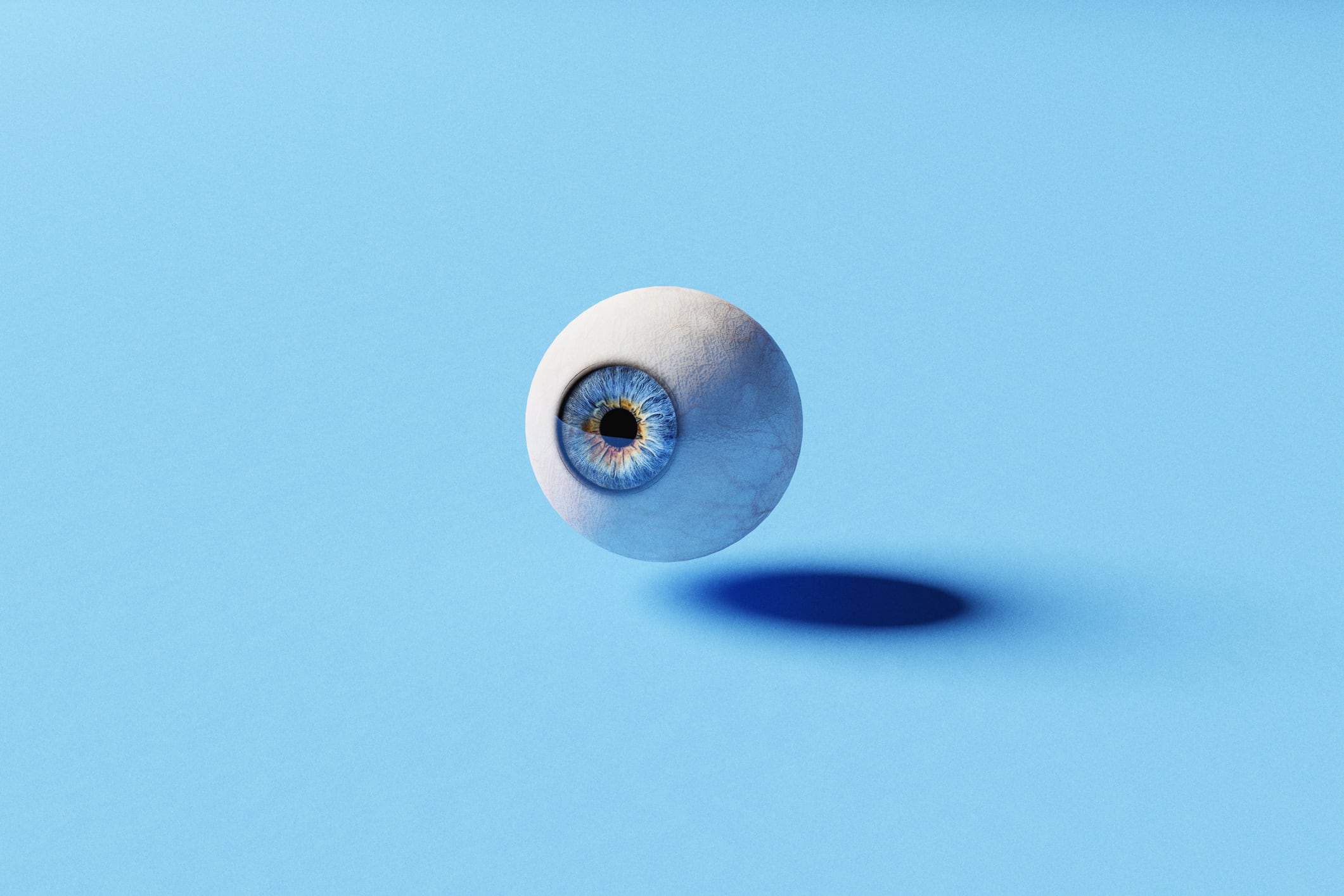 Single blue eye ball floating on a blue background