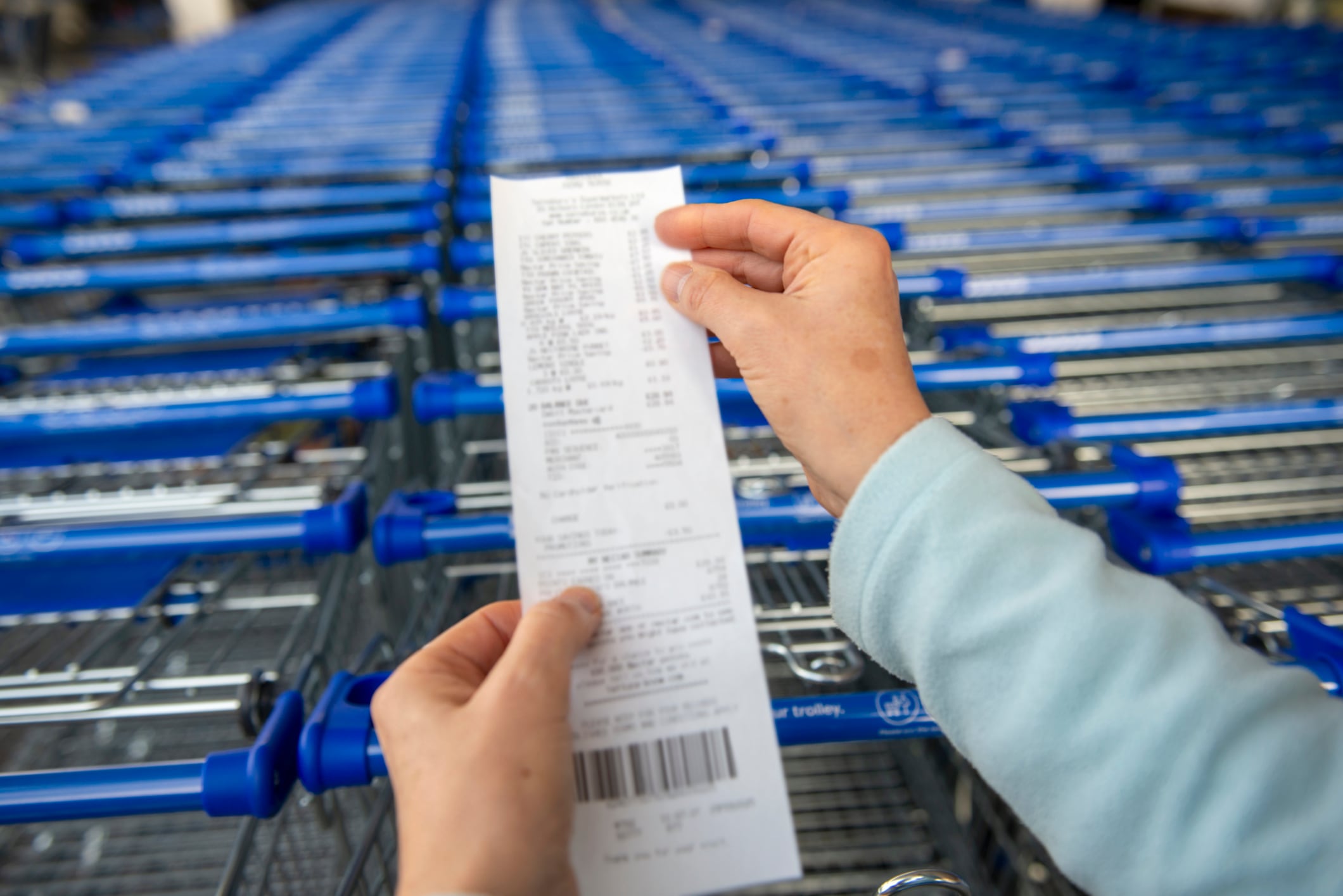 Shoppers point of view of supermarket receipt and trolleys. (Details Blurred.)