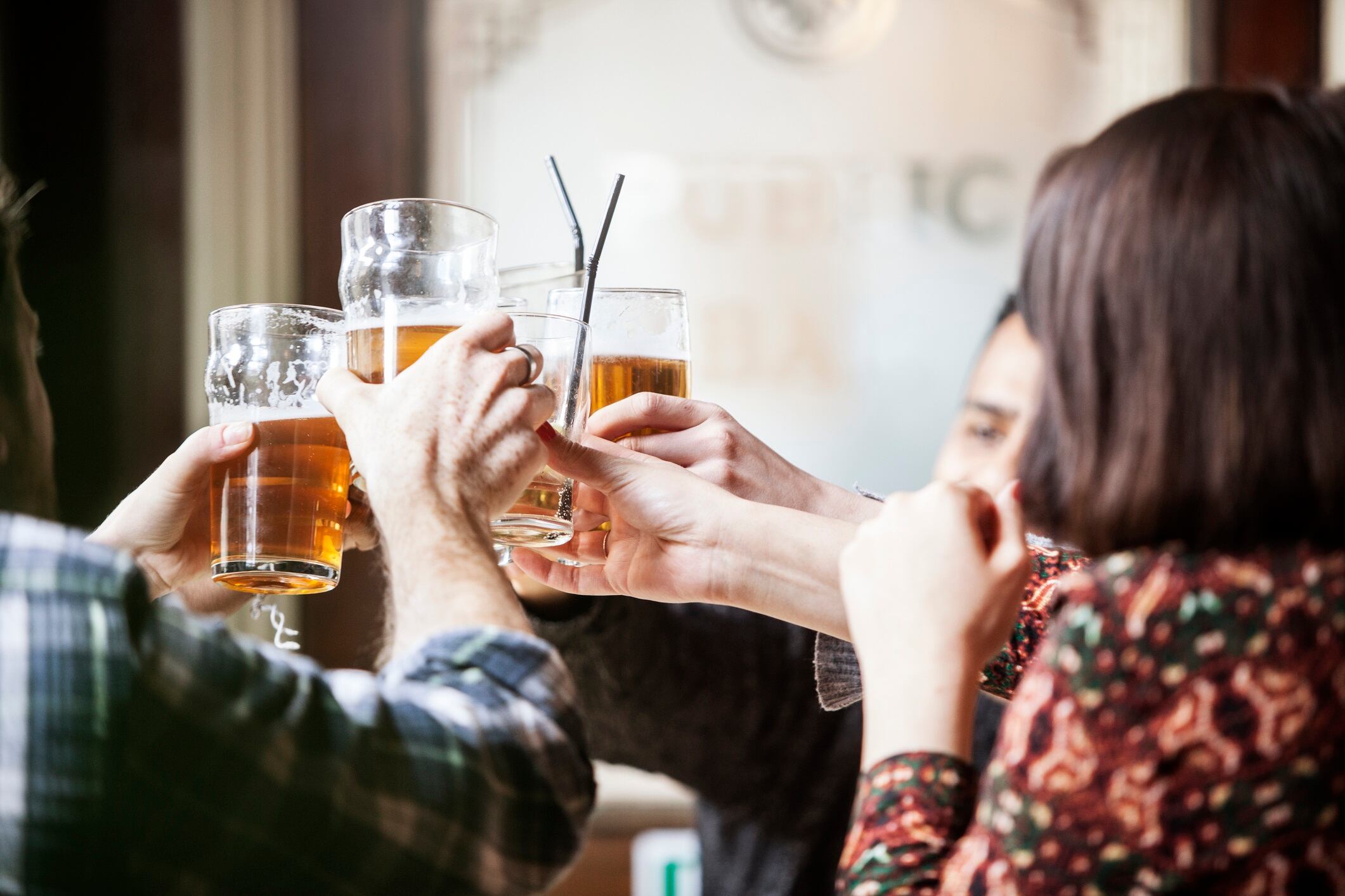A group of friends toasting with beer mugs at a pub