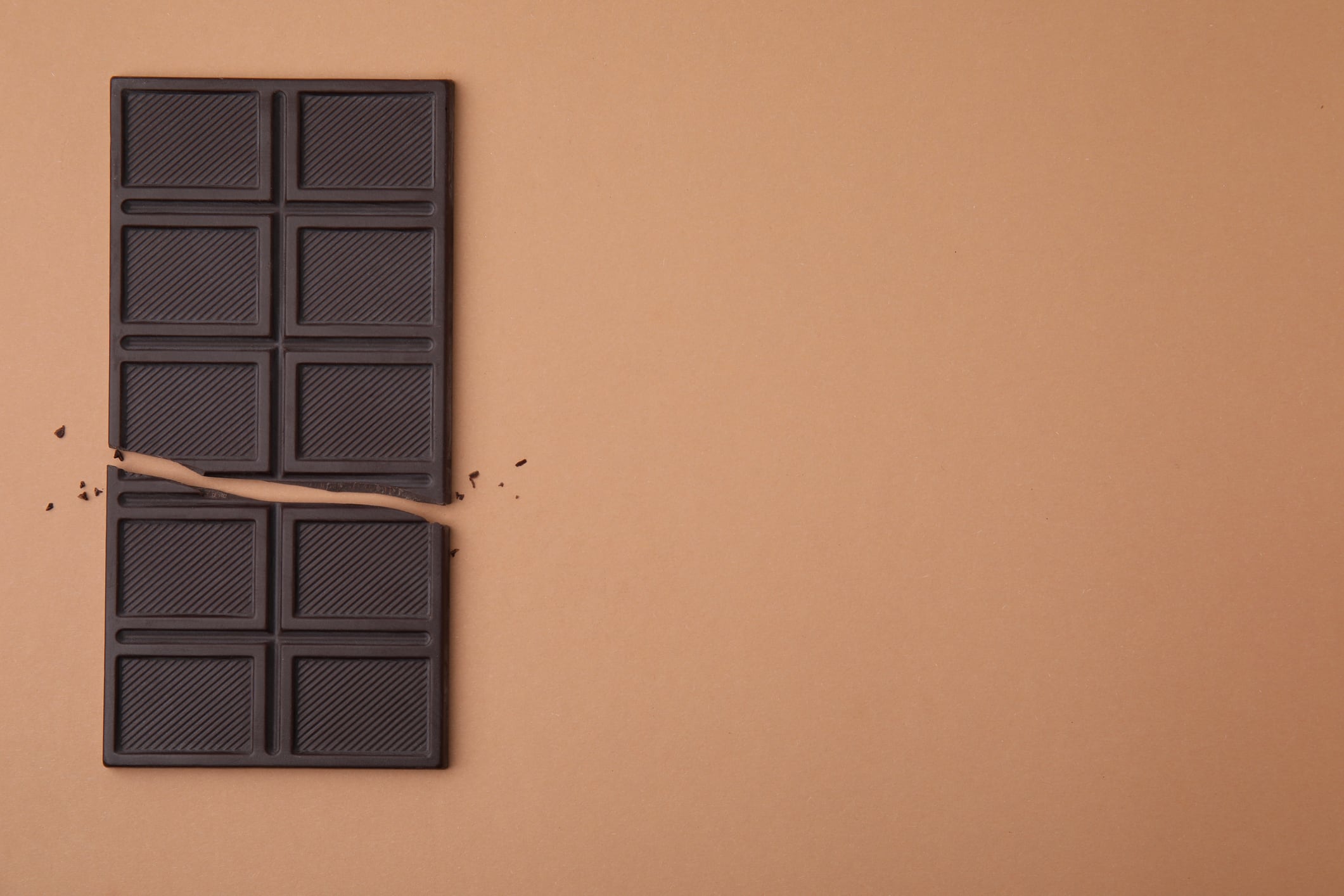 Broken chocolate bar on brown background, top view. Space for text