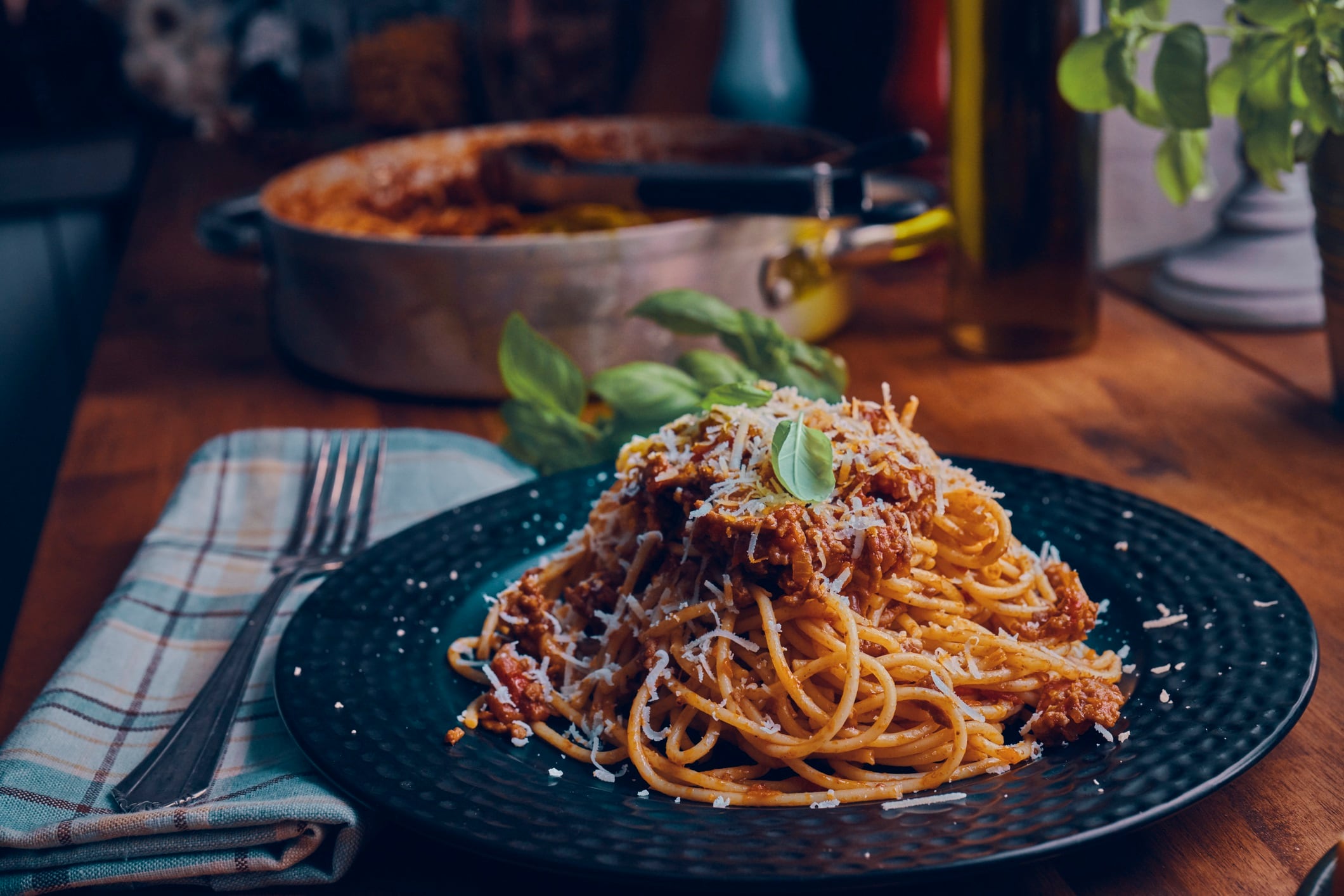 Plate of spaghetti bolognaise with parmesan and basil on top.
