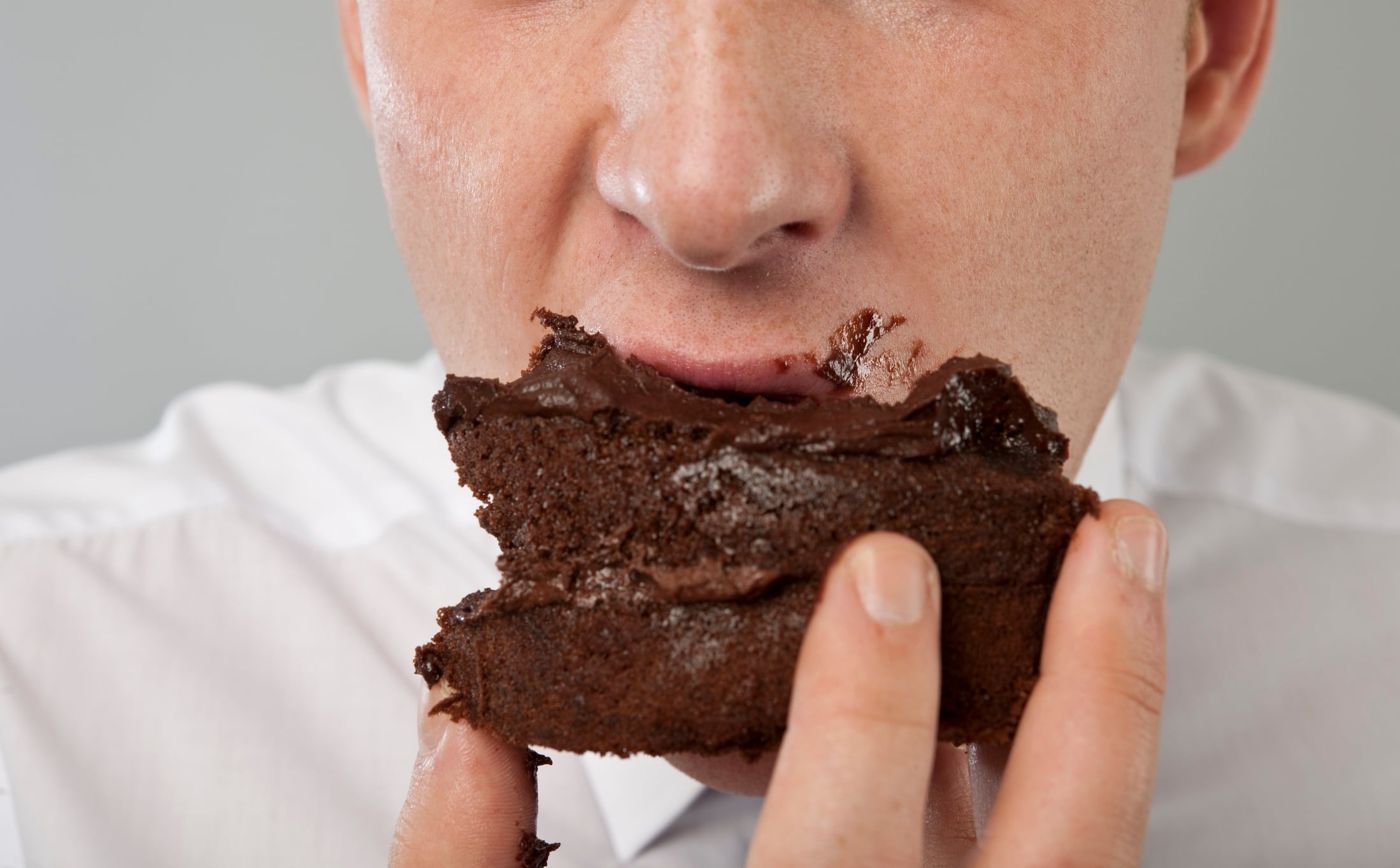 Close up of mans mouth eating chocolate cake