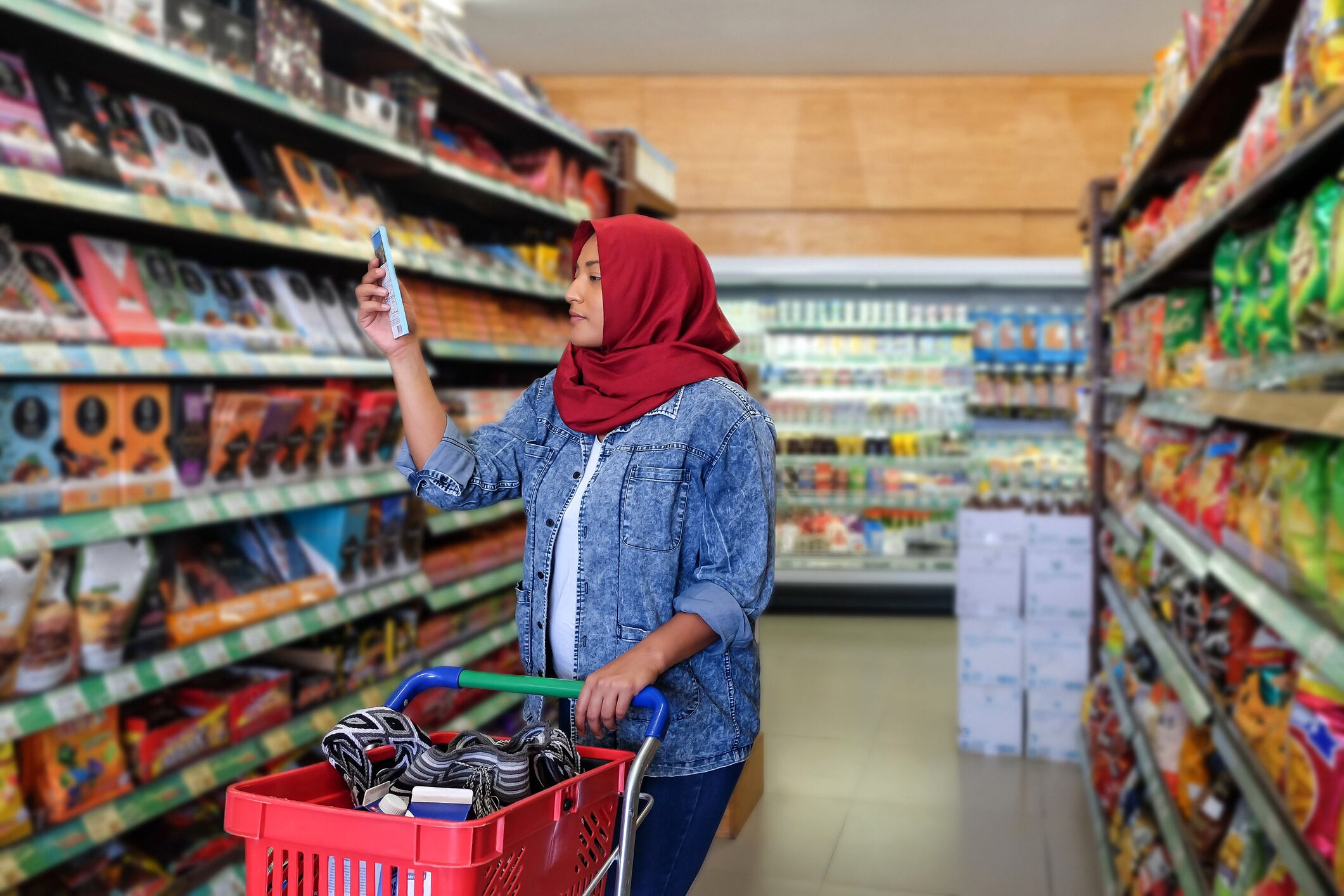 Photo of a woman reading food label of a chocolate bar during her weekly grocery shopping