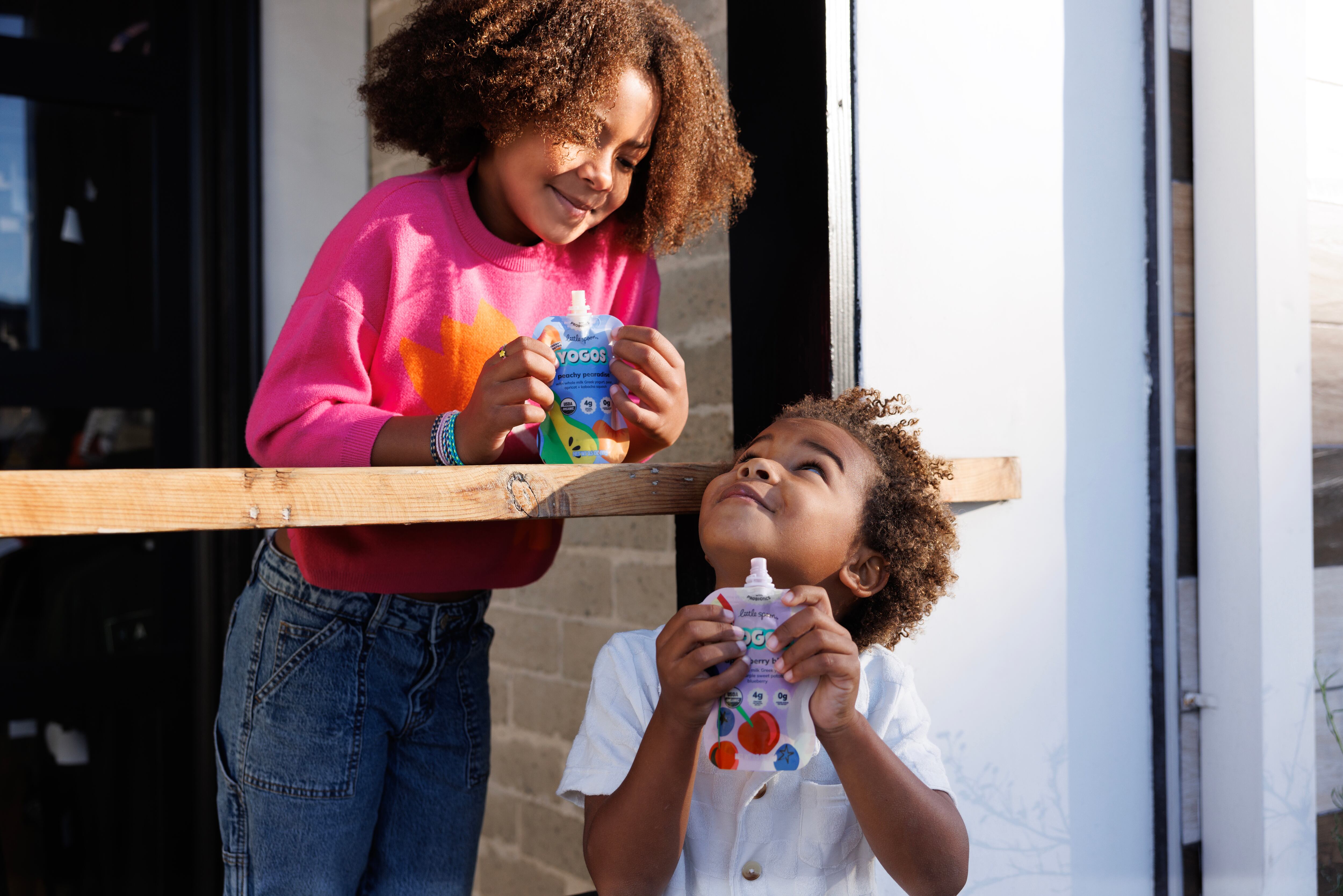 Two kids enjoying YoGos yogurt pouches.