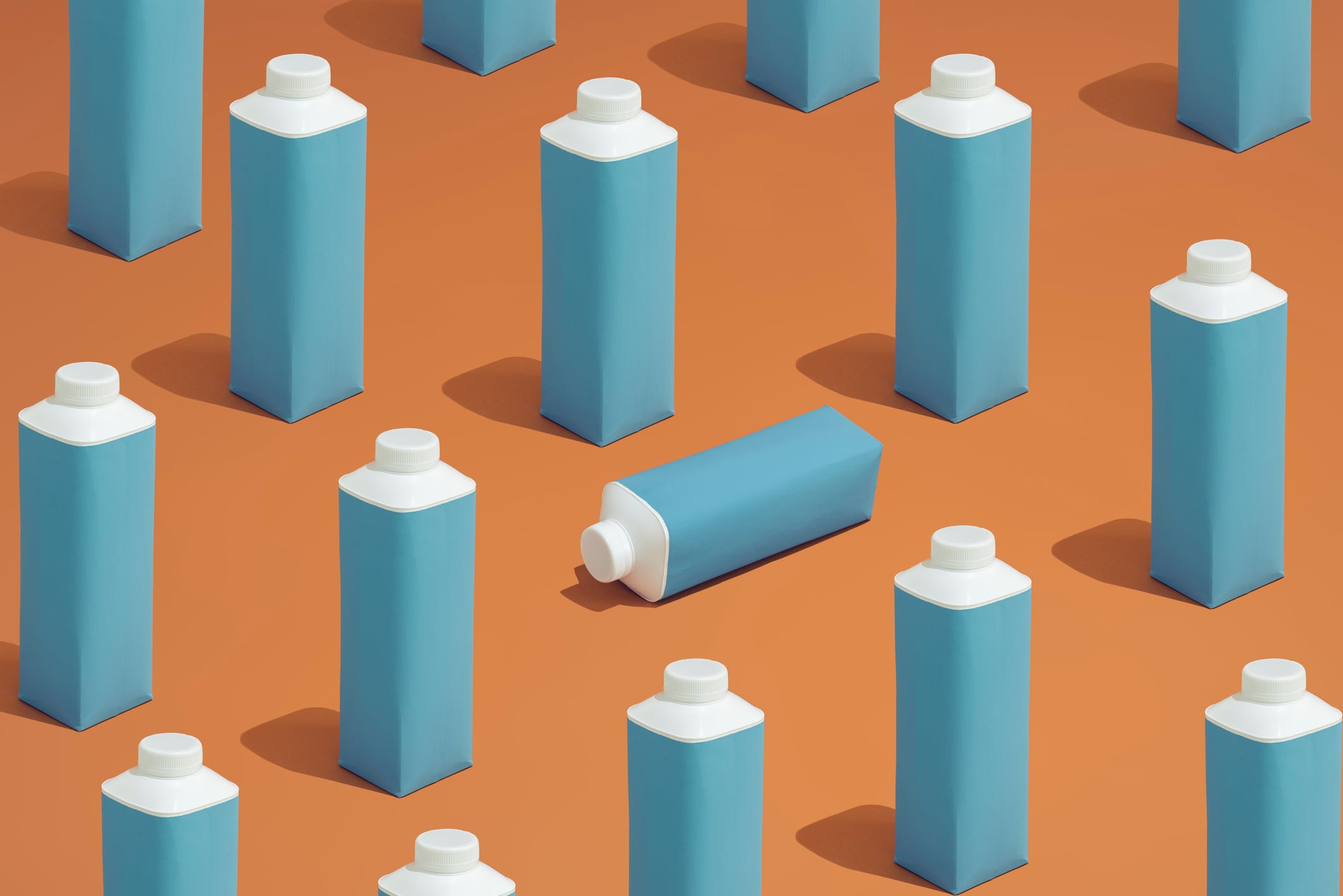 A group of blue and white packaging containers laid in a repetative pattern  on a colorful background