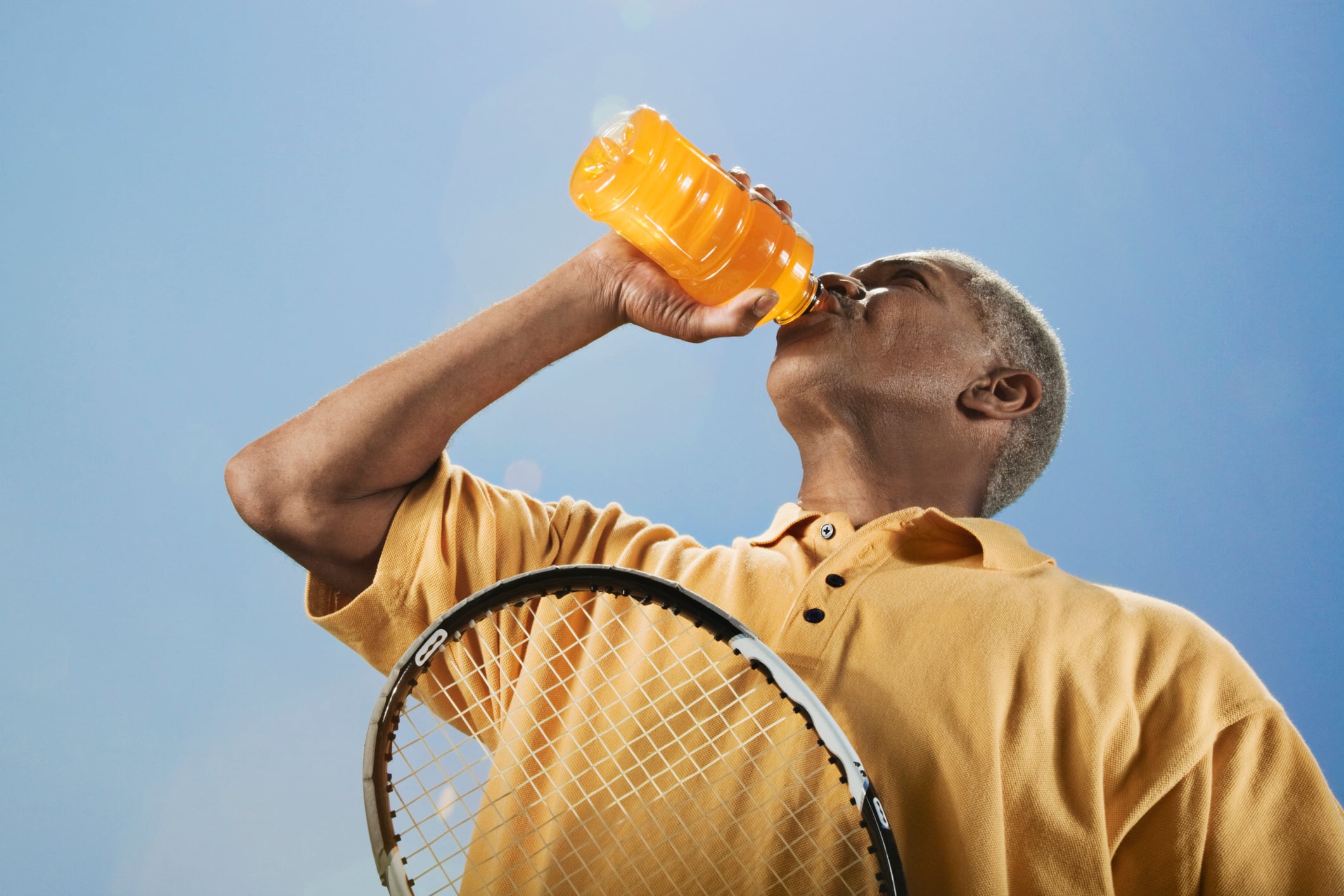Man drinking functional drink with tennis racquet