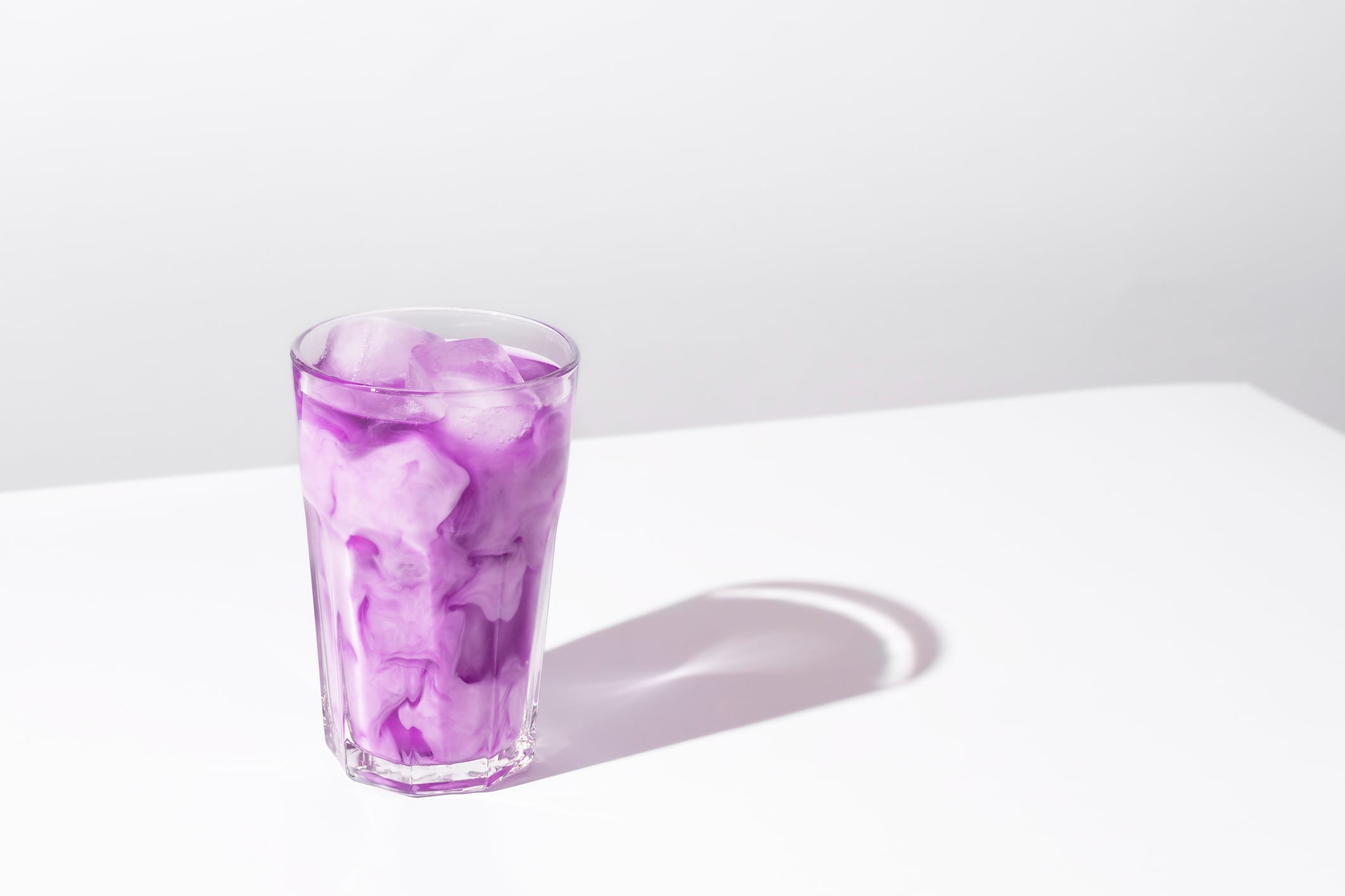 Iced coffee lavender drink on white background. Lavender purple honey latte.