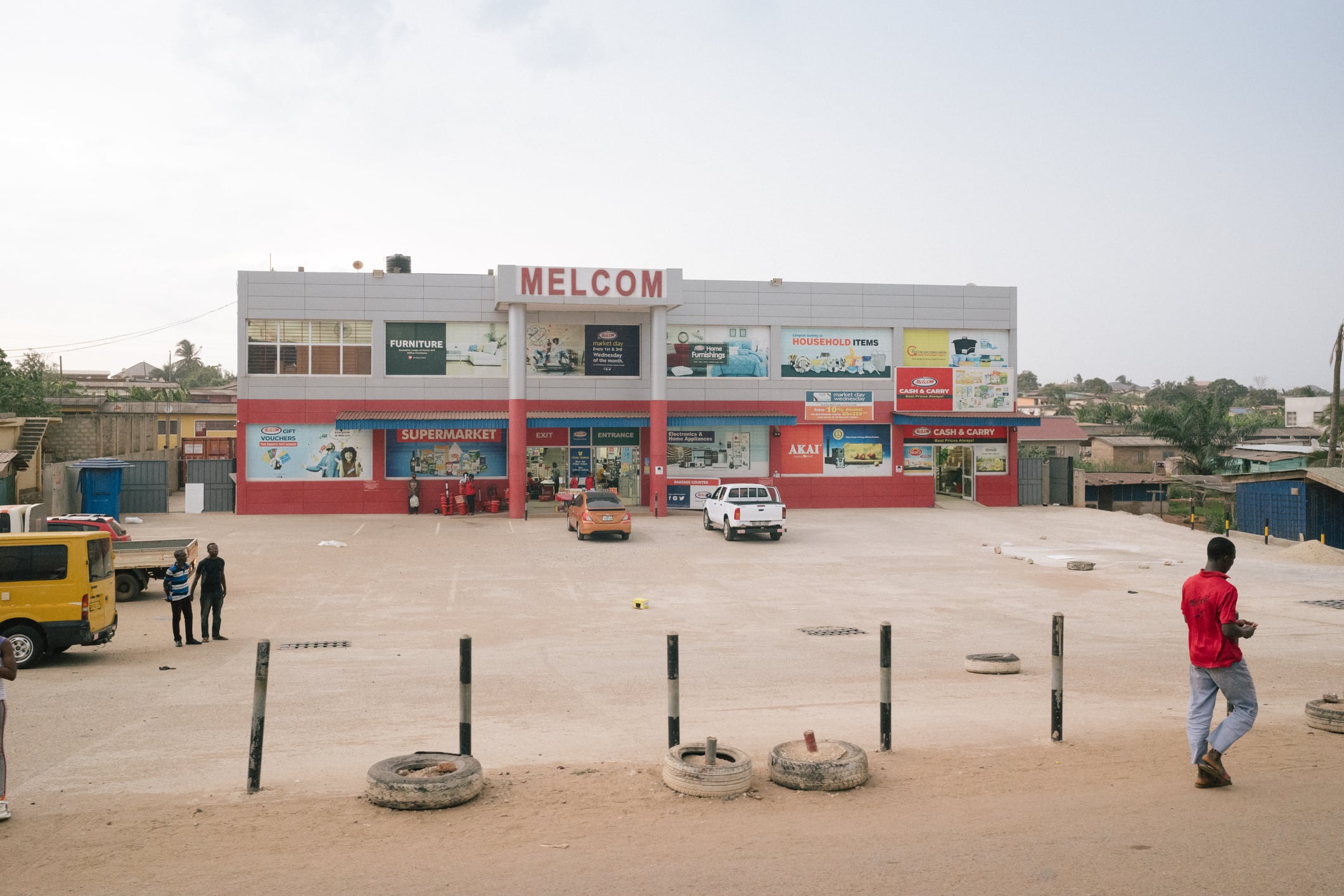 Cape Coast, Ghana - 19 Februar 2022: Everyday street scenes in Tema, wider region of Accra, a male pedestrian walks by a Melcom supermarket