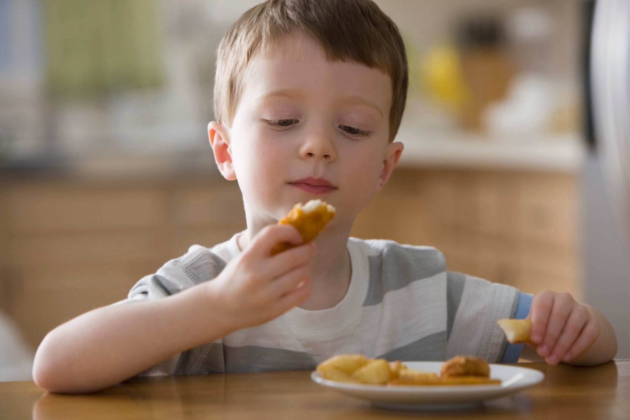 Caucasian boy eating chicken nuggets