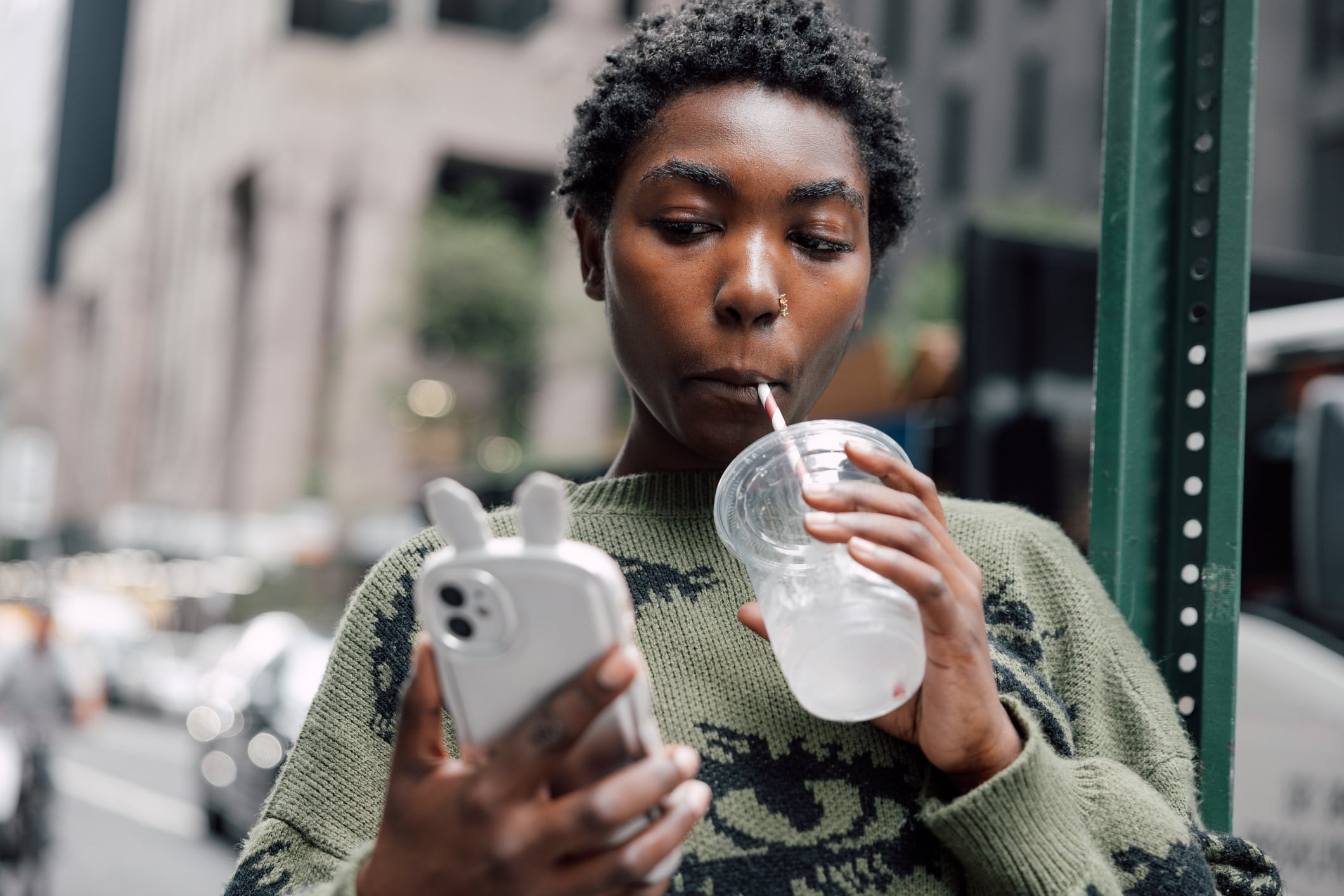 Young woman drinking a soft drink by the sidewalk in New York midtown Manhattan.