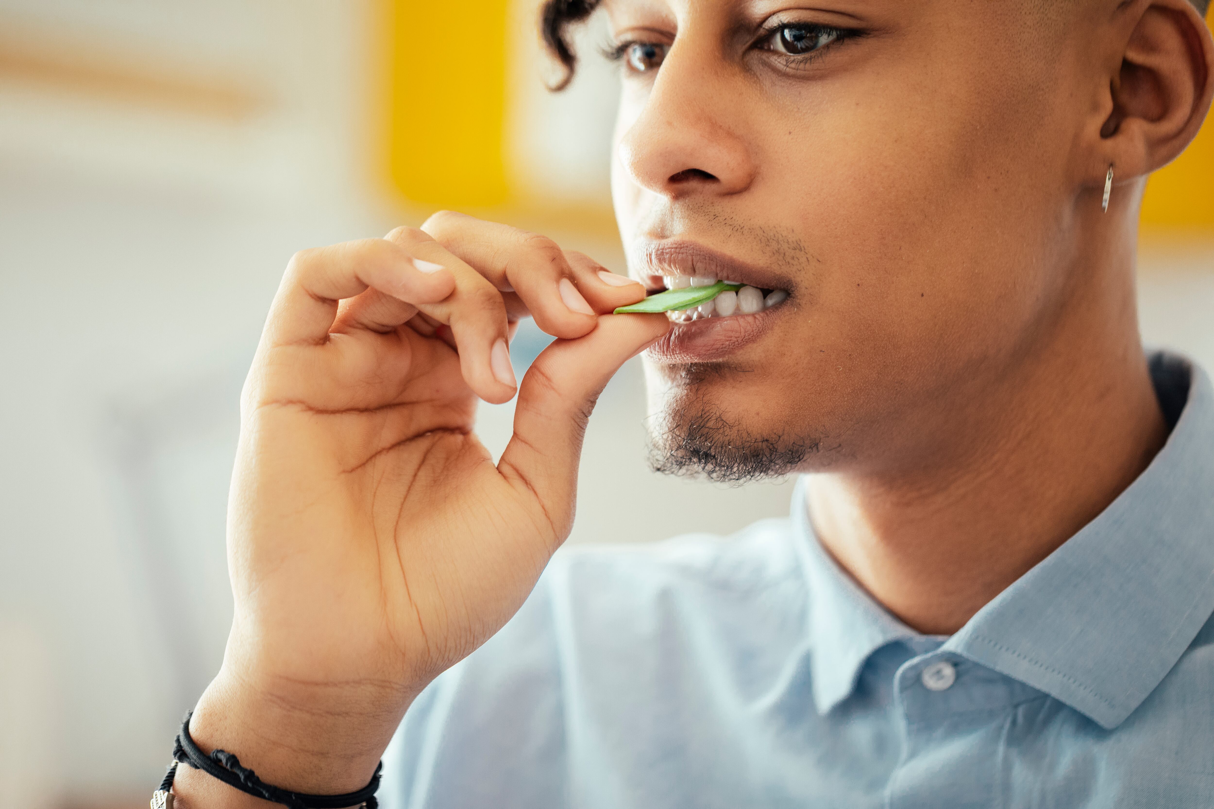 A young man putting a piece of chewing gum in his mouth.