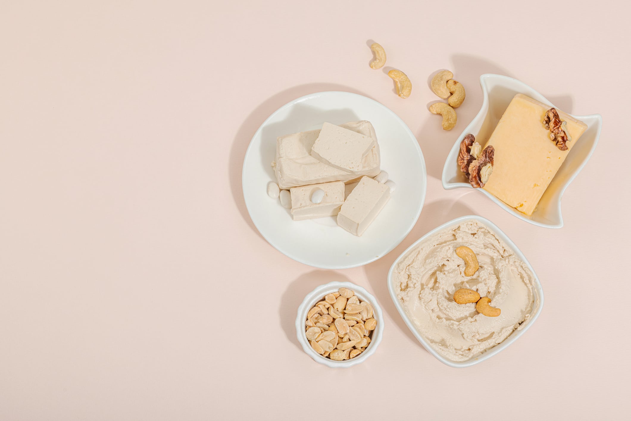 Set of assorted homemade vegan nuts cheese. Raw healthy sauce in a bowl, lactose free food. Bio organic product, plant based diet, alternative lifestyle. Gentle peach background, top view