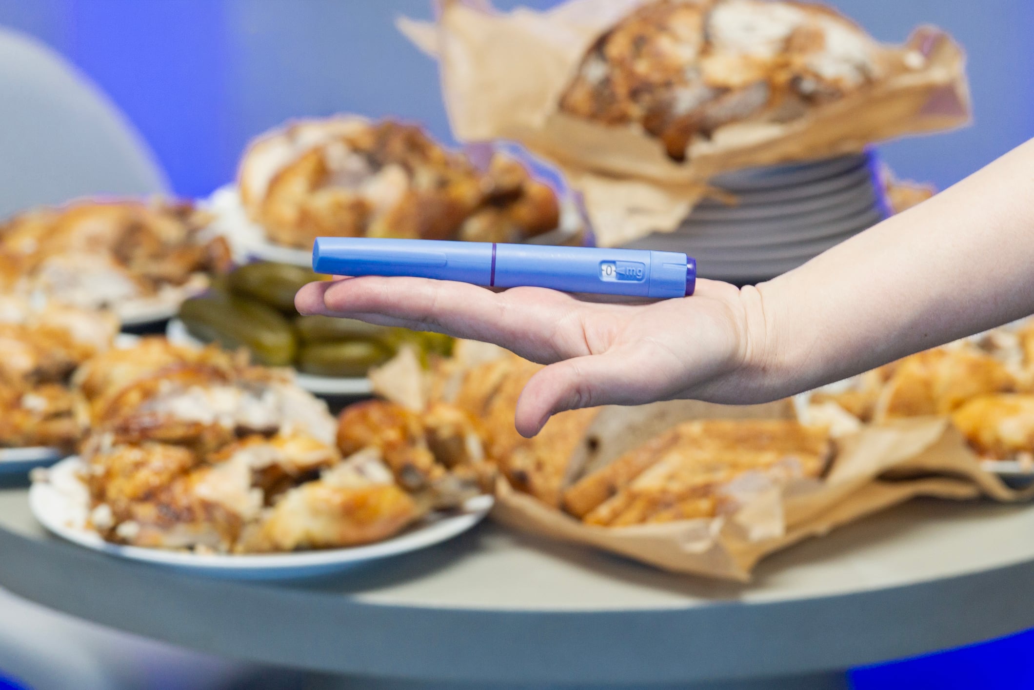 holding weight loss injection pen semaglutide glp-1 medication blue plastic device on hand background with roasted chicken food healthy lifestyle concept of healthcare, medicine, pharmacy.